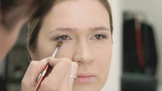 Makeup artist making make-up for young model