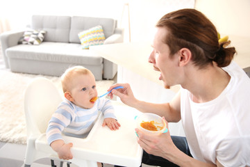 Obraz na płótnie Canvas Father feeding his baby son