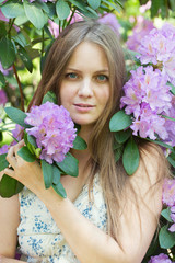 beautiful young woman and blooming rhododendron