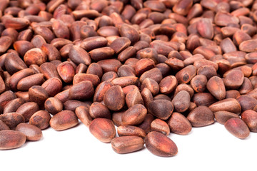 unpeeled pine nuts on a white background