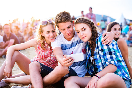Teenagers at summer music festival, taking selfie with smartphon