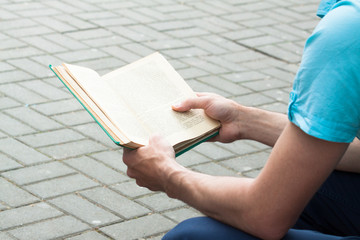 Man reading a book on the street.