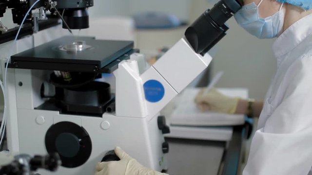 doctor looks into microscope in medical laboratory