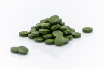 green spirulina chlorella seaweed pills close up on white