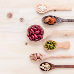 Assortment of beans and lentils in wooden spoon on wooden backgr