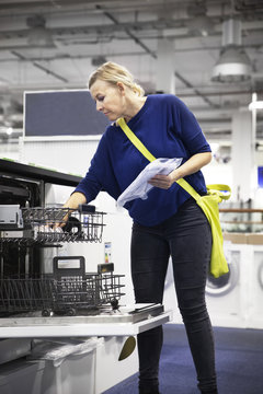 Woman looking at dishwasher in shop