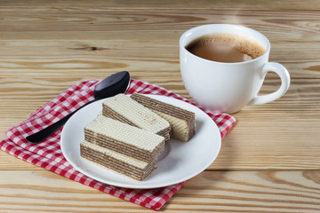 Wafers with chocolate and cup of hot coffee on rustic table