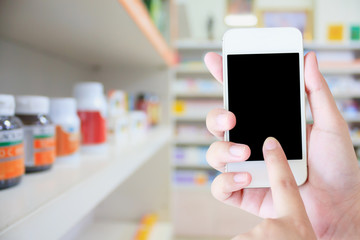 women using smartphone in the pharmacy blurred background