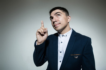 Handsome young business man pointing finger up.