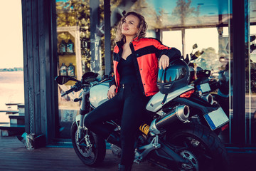 Naklejka na ściany i meble Blond female posing near motorcycle.