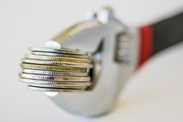 Wrench and coins . The concept of financial reliability .