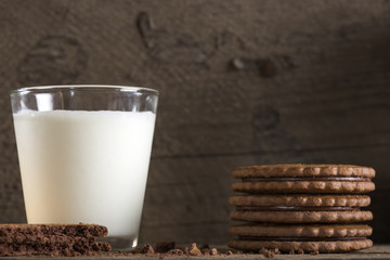 Glass of milk and chocolate biscuits on wooden table