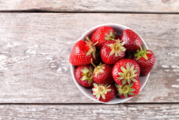 strawberries in a bowl on old table top view