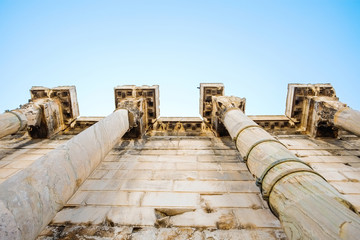 Looking up view of famous Greek temple pillars against clear blue sky in Greece