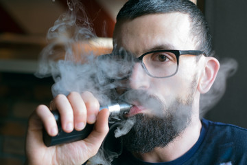 Bearded man smoking vaporizer and blows smoke
