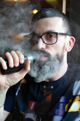 Bearded man smoking vaporizer and blows smoke