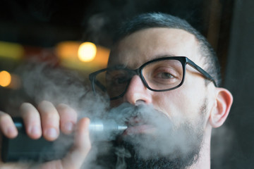 Bearded man smoking vaporizer and blows smoke