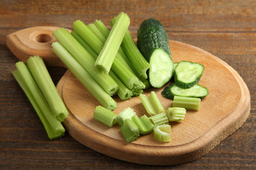 Fresh sliced green celery on wooden cutting Board with cucumber on brown wooden background