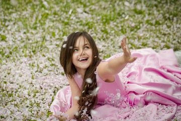 Naklejka na ściany i meble Little girl on green grass with petals