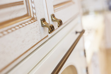 Obraz premium Golden furniture handle, on white wooden kitchen cabinet . Small depth of field