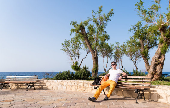 guy sitting on a bench near the sea
