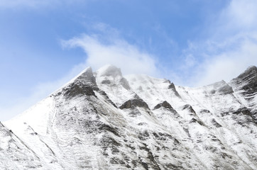 snowy mountain peak peaks of mountain surrounded by clouds