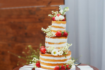 three-tiered wedding cake with strawberries on table