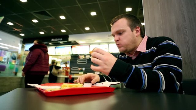 Man Eating Fastfood Burger And French Fries