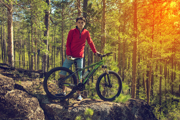 Naklejka premium Man with the bike standing on a rock