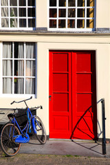 Fototapeta na wymiar Red door and blue bicycle in old european house, Amsterdam.