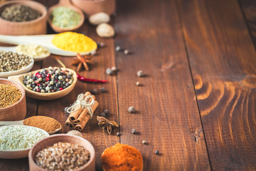 Beautiful colorful spices in wooden spoons on an old wooden brown table. Free space for your text