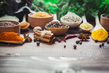 Beautiful colorful spices in wooden spoons and bowls with lettuce, dill and Basil on an old wooden...