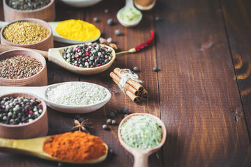 Beautiful colorful spices in wooden spoons on an old wooden brown table. Free space for your text