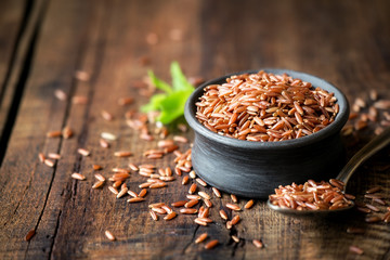 Red rice an a small ceramic bowl against dark rustic wooden background