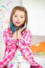 Portrait of a cute cheerful happy little girl showing her hands painted in bright colors
