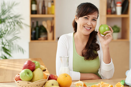 Portrait of cheerful mature Vietnamese woman holding green apple