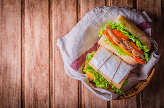 Homemade sandwich with fresh tomatoes and chicken breast in basket on wooden background. Selective focus. Top view. ackground with place for some text. Picnic concept