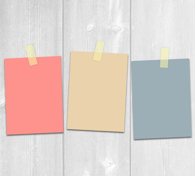 Three colored adhesive paper on a white wooden background design template.
