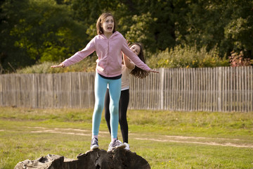 Playing. Two sisters are pretending to push each other off an old dead tree trunk. They are mucking...