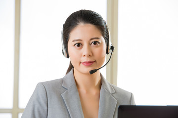Smiling Asian woman with a headphone and working on laptop