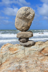 Fototapeta na wymiar Rock balancing over a cliff on a shore near the rough sea