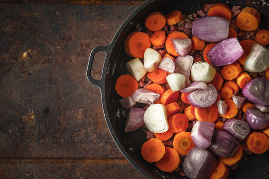 Shallot and carrots in the pan on the metal background