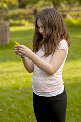 Obraz premium Autumn Leaf. A young girl examines a small autumn leaf that has turned yellow. She has been running around and is happy and free in the park.
