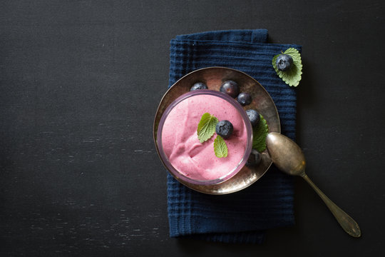 Mixed berry mousse served in glass with blueberries and lemon balm. Selective focus.