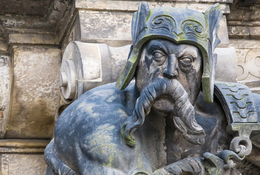 eine Sandsteinskulptur zeigt einen barbarischen Krieger