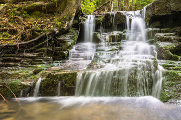 waterfall between mossy rocks. beautiful forest stream