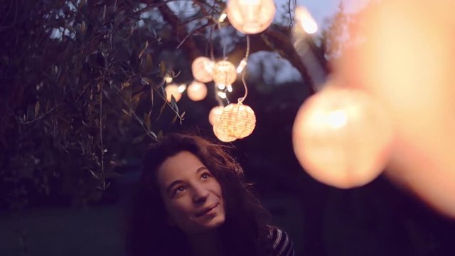 slow motion shot of young woman playing with lantern in the garden

