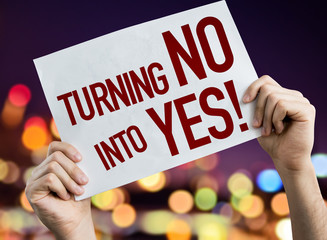 Turning No Into Yes placard with night lights on background