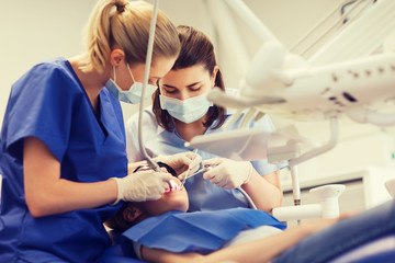 Obraz na płótnie Canvas female dentists treating patient girl teeth