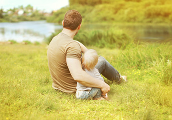 Happy father and son resting sitting together on grass summer ne